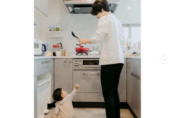 キッチンに立つ女性と座っている子供